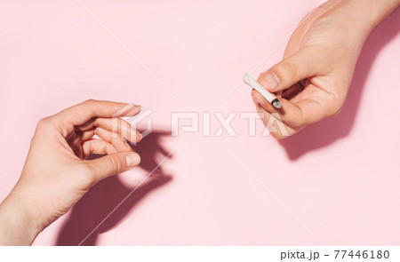 Passing cannabis cigarette from hand to hand. Cannabis smoking concept. pastel colour photo of Hands giving each other smoldering paper cigarette Passing cannabis cigarette from hand to hand. Cannabis smoking concept. pastel colour photo of Hands giving each other smoldering paper cigarette 77446180