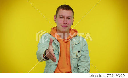 Friendly man outstretching hand to camera, offering handshake, greeting with kind smile, welcoming Friendly man outstretching hand to camera, offering handshake, greeting with kind smile, welcoming 77449300