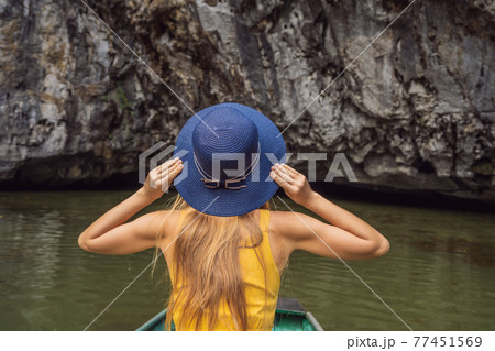 Woman tourist in boat on the lake Tam Coc, Ninh Binh, Viet nam. It's is UNESCO World Heritage Site, renowned for its boat cave tours. It's Halong Bay on land of Vietnam. Vietnam reopens borders after 77451569