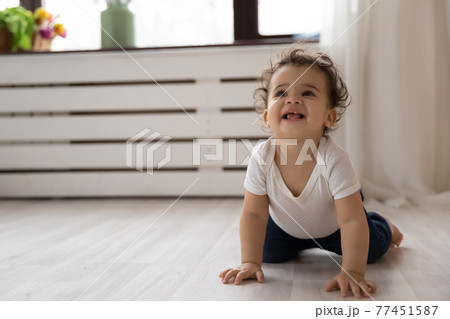 Smiling African American baby child crawling on floor 77451587