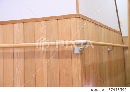 屋内にある廊下の曲がり角の腰板に木製の手すり 77453592
