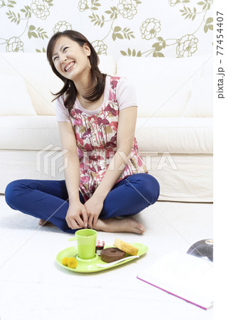 ソファーの前に座る笑顔の女性 77454407