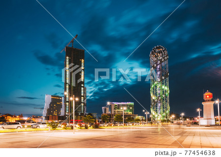 Batumi, Adjara, Georgia. Illuminated Alphabet Tower And Lighthouse At Promenade Near Miracle Park, Amusement City Park On Evening Or Night. Blue Hour. Modern Urban Architecture Batumi, Adjara, Georgia. Illuminated Alphabet Tower And Lighthouse At Promenade Near Miracle Park, Amusement City Park On Evening Or Night. Blue Hour. Modern Urban Architecture 77454638