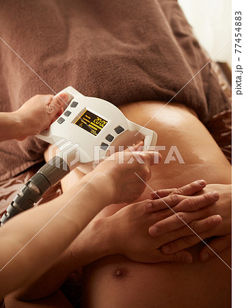 機械でお腹のマッサージを受けるアジア人男性 77454883