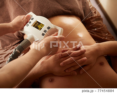 機械でお腹のマッサージを受けるアジア人男性 77454884