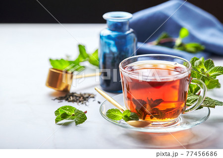 Black tea in glass transparent mug with mint leaves. Soothing tea, anti-stress 77456686