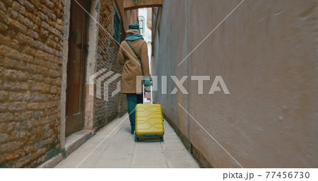 Woman with trolley back walking along the alleyway Woman with trolley back walking along the alleyway 77456730