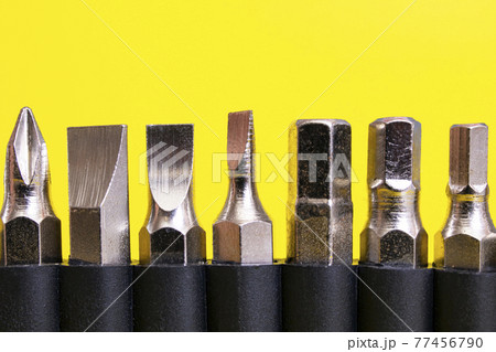Screwdriver bits in a row on yellow background Screwdriver bits in a row on yellow background 77456790