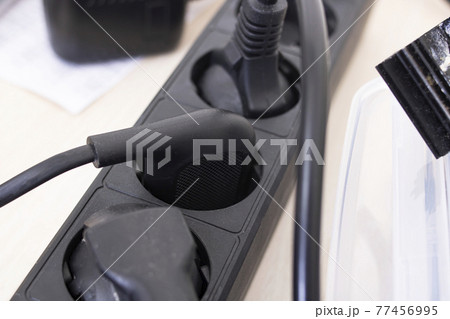 Black extension cord with button and wires on white background 77456995