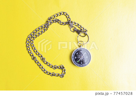 Compass with chain on a yellow background Compass with chain on a yellow background 77457028