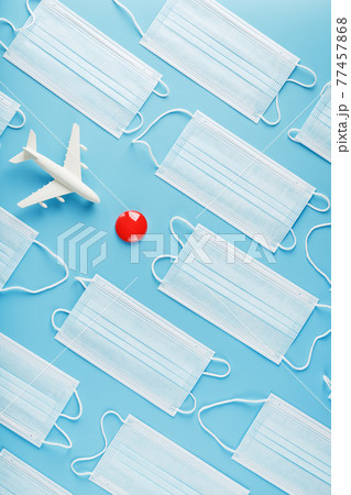 A toy white airplane and protective masks on a blue background with a red dot as the destination. A toy white airplane and protective masks on a blue background with a red dot as the destination. 77457868
