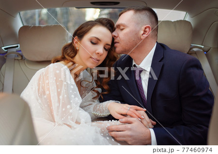 The bride and groom in the back seat of the car. Renting a car for a wedding. 77460974