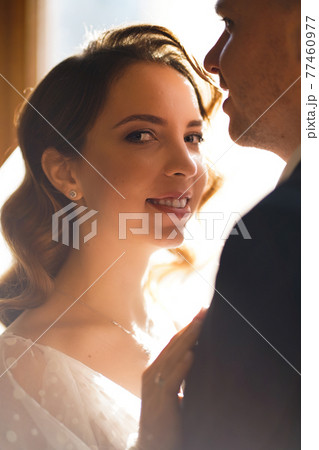 silhouettes of the bride and groom in sunlight through the glass in the door. 77460977