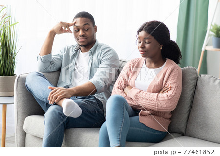 Frustrated black woman sitting apart from her frustrated boyfriend 77461852
