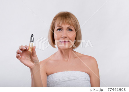 Beauty routine procedures. Sensual mature woman showing bottle with anti-aging serum on light studio background 77461908