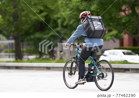 自転車で走行するデリバリー配達員 77462290