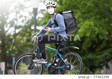 マスクを装着して自転車に乗る配達員 マスクを装着して自転車に乗る配達員 77462299