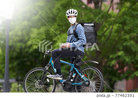 マスクを装着して自転車に乗る配達員 マスクを装着して自転車に乗る配達員 77462301