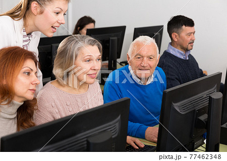 Young and mature partners grouped around computer monitor Young and mature partners grouped around computer monitor 77462348