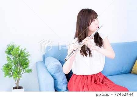 ソファでフルートを吹く女性 77462444