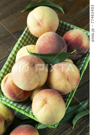 Fresh harvest of peaches in a basket on a wooden rustic table.  77463493