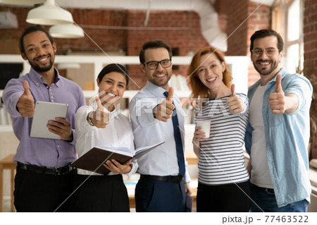 Smiling diverse employees group showing thumbs up, looking at camera Smiling diverse employees group showing thumbs up, looking at camera 77463522