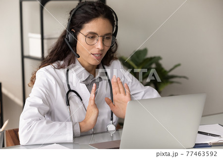 Confident female therapist in headphones consult patient by video call 77463592