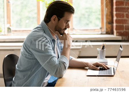 Side view thoughtful businessman in glasses looking at laptop screen 77463596