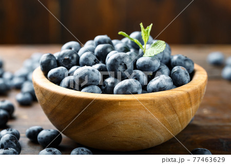 Juicy and fresh blueberries with green leaves on a rustic table. Vegan and vegetarian concept. Juicy and fresh blueberries with green leaves on a rustic table. Vegan and vegetarian concept. 77463629
