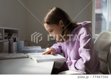 Concentrated young teenage girl reading textbook at home. Concentrated young teenage girl reading textbook at home. 77467560