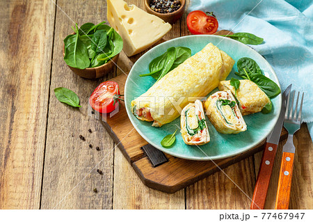 Japanese cuisine. National Japanese dish Omelet tamago yaki for breakfast. Rolled egg with spinach, tomato and cheese on a wooden table. Copy space. 77467947