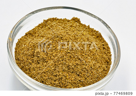 Ground cumin or coriander in glass bowl closeup against white 77469809