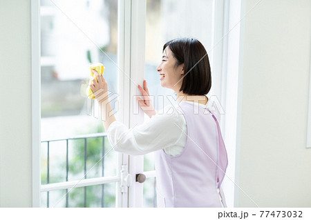 窓拭きをするかわいい女性 77473032