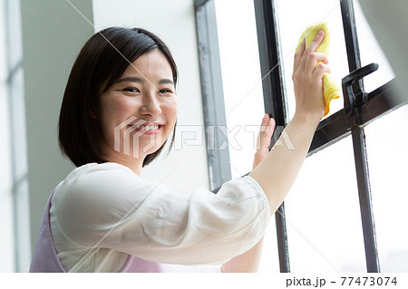 窓拭きをするかわいい女性 窓拭きをするかわいい女性 77473074