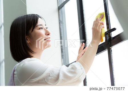 窓拭きをするかわいい女性 77473077