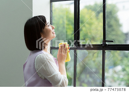 窓拭きをするかわいい女性 窓拭きをするかわいい女性 77473078