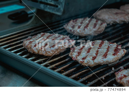Smoky hamburger meat grilling on fire for burgers. BBQ Grilled Burgers Patties. 77474894