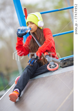 Vertical photo of a teenager dirl drinking water from plastic bottle. 77474952