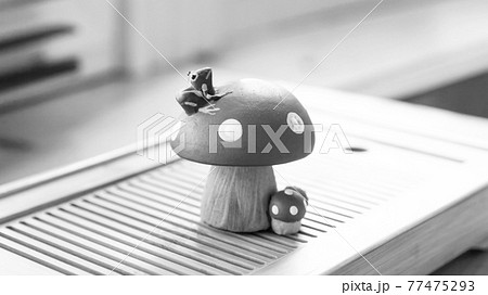 A small frog sitting on a fly agaric. Clay tea figurine, teapet. Black and white photo. 77475293