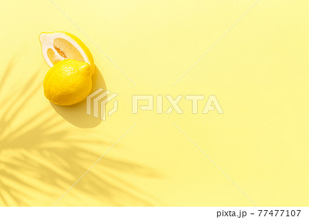 Two halved cuts of lemon with shadow from palm leaf on yellow background Two halved cuts of lemon with shadow from palm leaf on yellow background 77477107