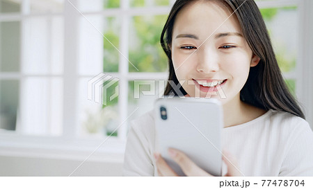 笑顔でスマホを見る女性 笑顔でスマホを見る女性 77478704