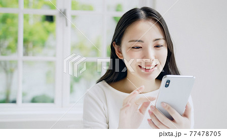 笑顔でスマホを見る女性 77478705