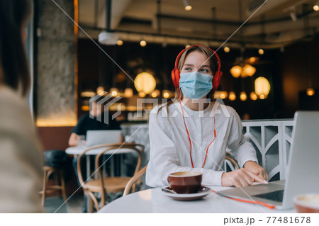 A girl sitting in a coffee shop with headphones. Coronavirus outbreak. 77481678