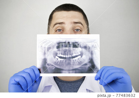 A dentist doctor examines a radiography of the teeth of a patient who has problems and teeth are inserted. The concept of research and diagnosis 77483632