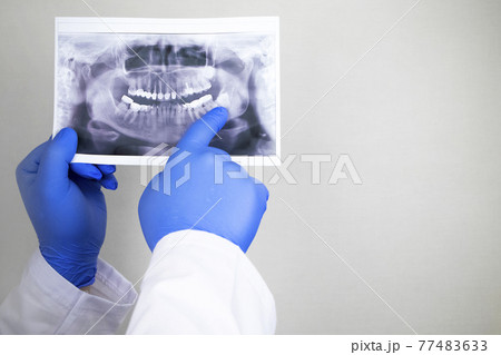 A dentist doctor examines a radiography of the teeth of a patient who has problems and teeth are inserted. The concept of research and diagnosis 77483633