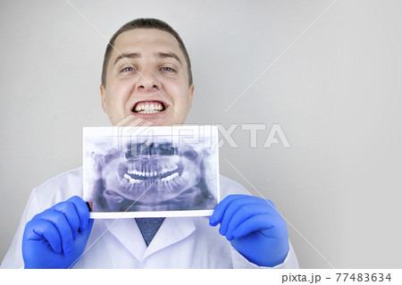 A dentist doctor examines a radiography of the teeth of a patient who has problems and teeth are inserted. The concept of research and diagnosis A dentist doctor examines a radiography of the teeth of a patient who has problems and teeth are inserted. The concept of research and diagnosis 77483634