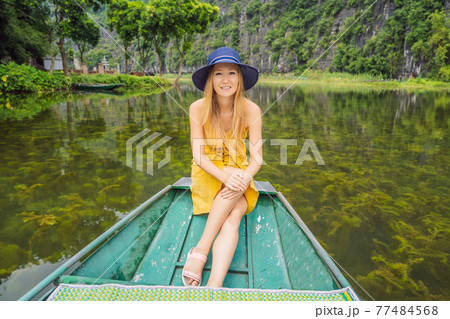 Woman tourist in boat on the lake Tam Coc, Ninh Binh, Viet nam. It's is UNESCO World Heritage Site, renowned for its boat cave tours. It's Halong Bay on land of Vietnam. Vietnam reopens borders after 77484568