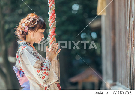 お参りする浴衣姿の女性 77485752