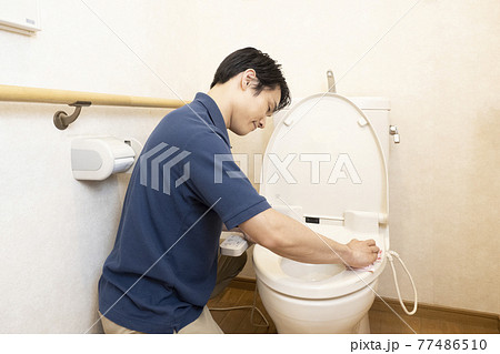 トイレの清掃をするハウスクリーニングの男性作業員の後ろ姿 77486510