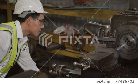 professional mechanical engineer or operation man wear uniform goggles safety working on workshop metal lathe industrial 77486703